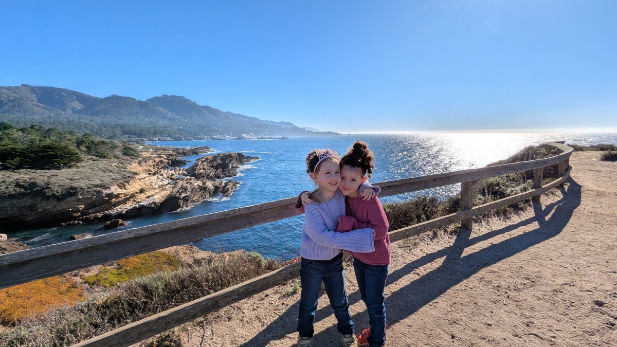 Alice and Emily hugging by the coast