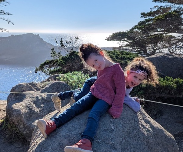 Alice and Emily on a rock by the ocean